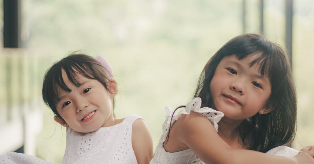 Delightful image of two young girls in white dresses smiling warmly outdoors.