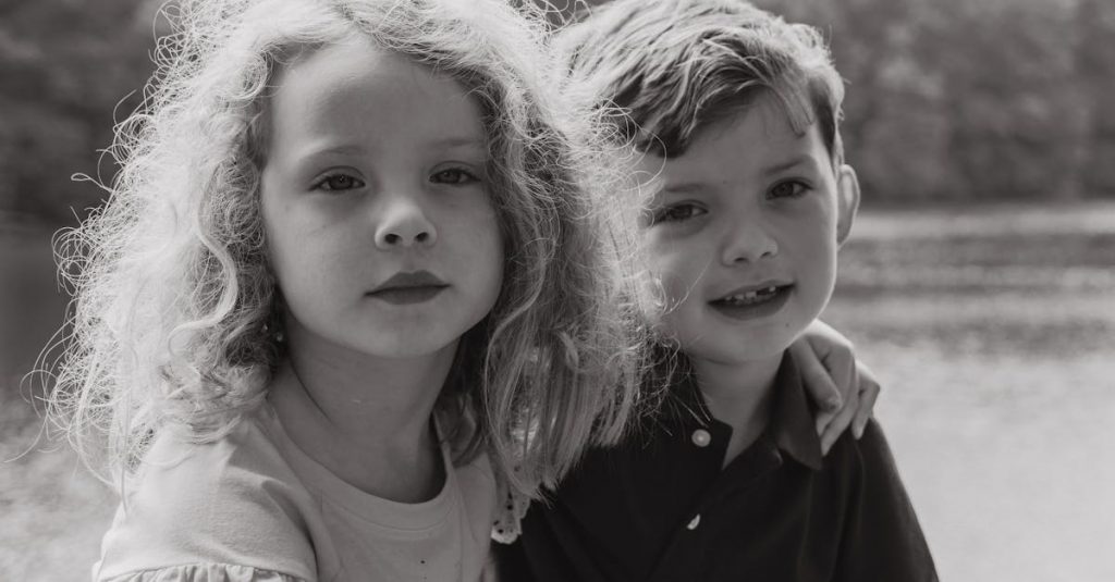 A black and white portrait of two kids by the water, capturing their friendship and togetherness.